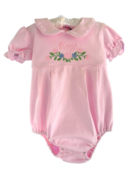 A pink baby romper with short puff sleeves, a Peter Pan collar, and floral embroidery on the chest reading 'Hope' with green leaves and blue flowers.